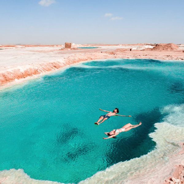 Casal feliz em um lago de sal em Siwa com águas cristalinas.